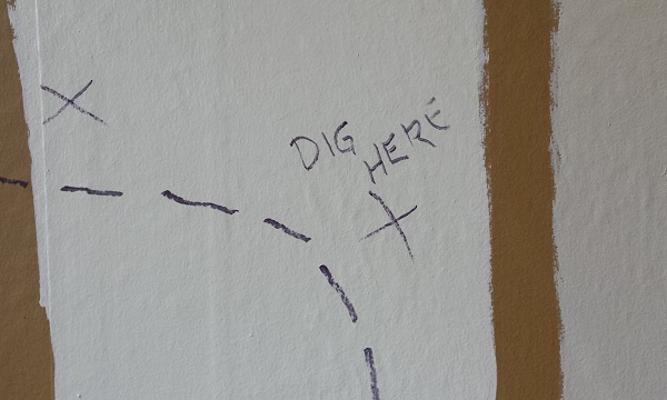 Wall showing plaster damage outlined in felt pen and the caption "dig here"