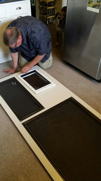 Man applies screen panel to wood door